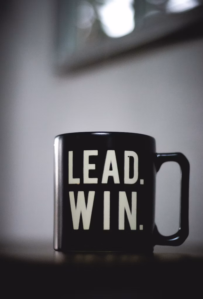 Black coffee mug with the word “Lead” written on it.